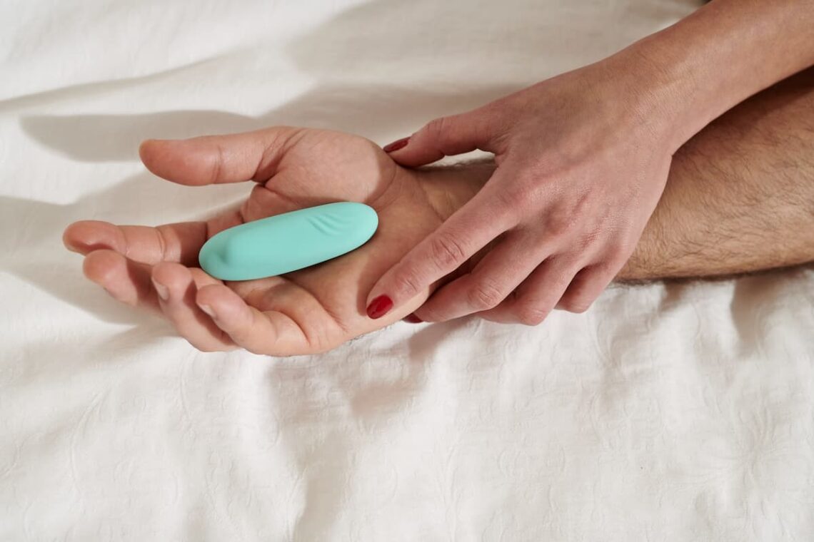 un sextoy godemichet bleu est posé dans la main d'un homme